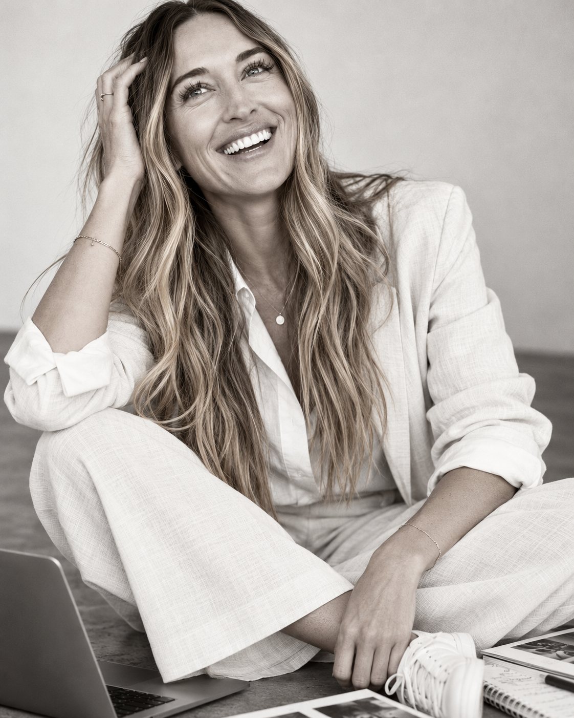Black-and-white portrait of Lauren LoBue laughing, seated on the floor beside a laptop and notebook
